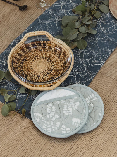 Blue and white oven mits on table with greenery and pie holder