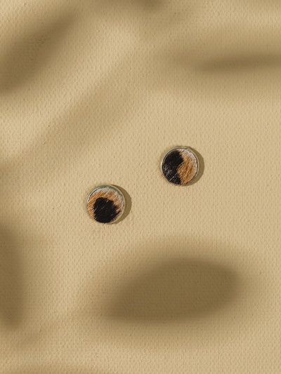 Three stud earrings on beige background