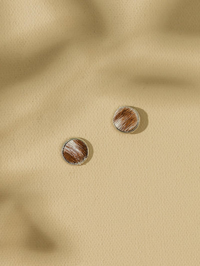 Three stud earrings on beige background