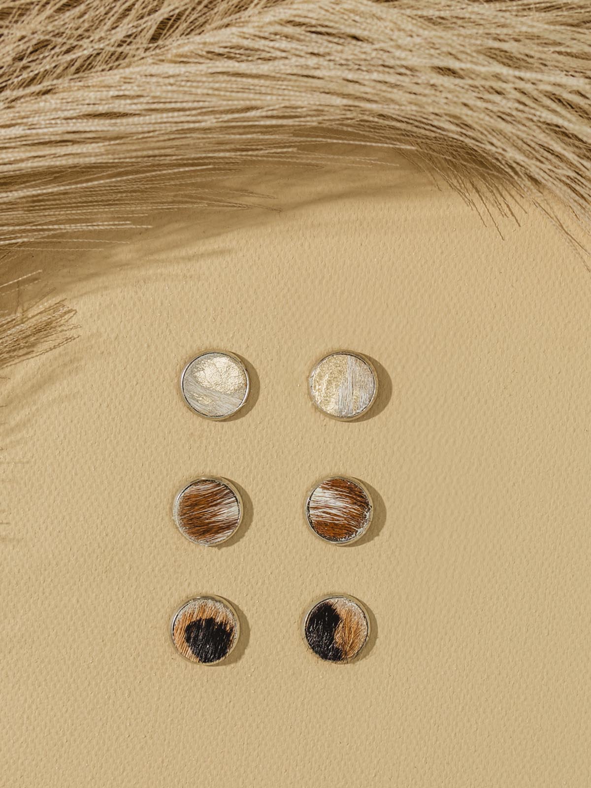 Three stud earrings on beige background