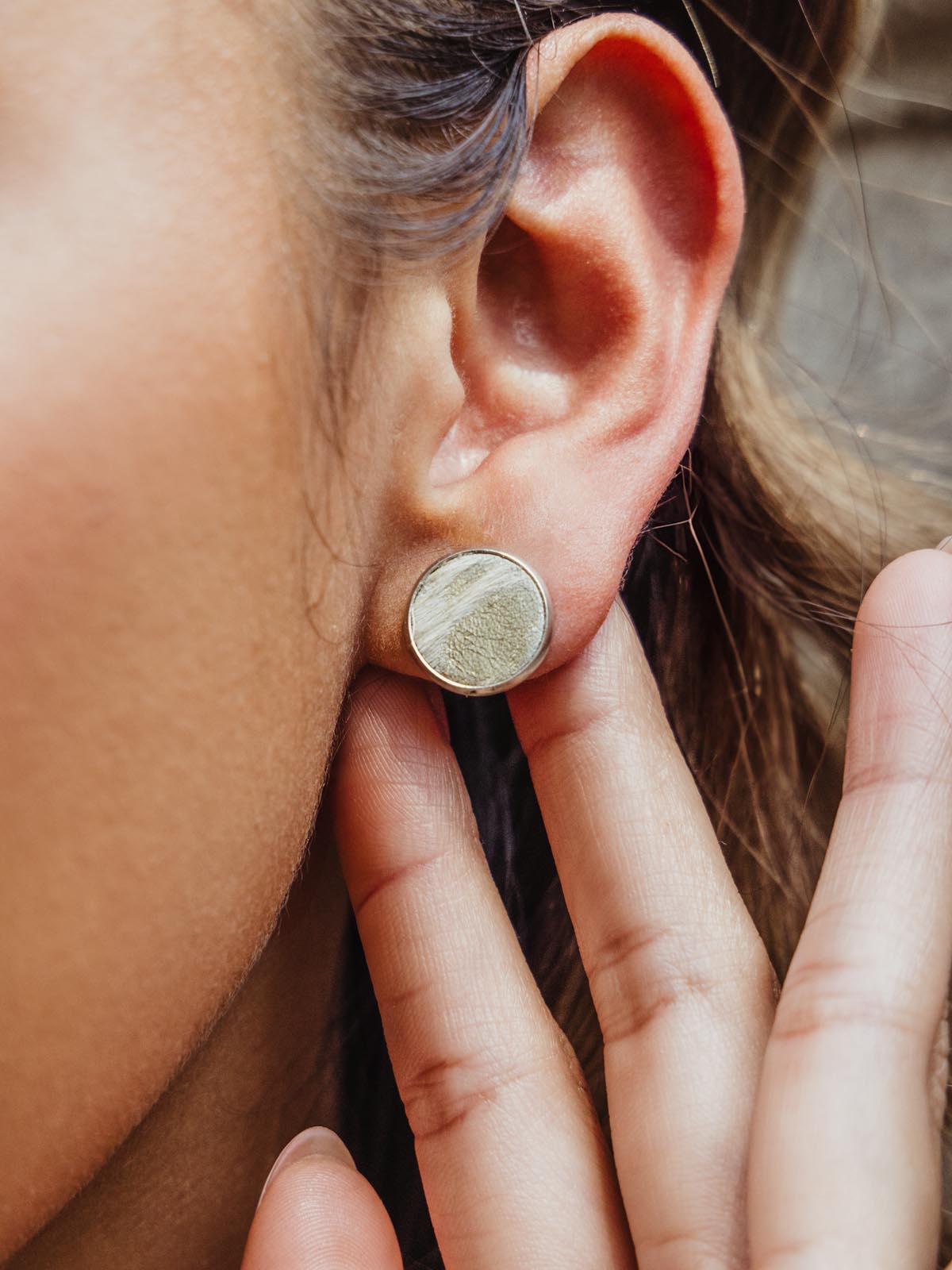 Three stud earrings on beige background