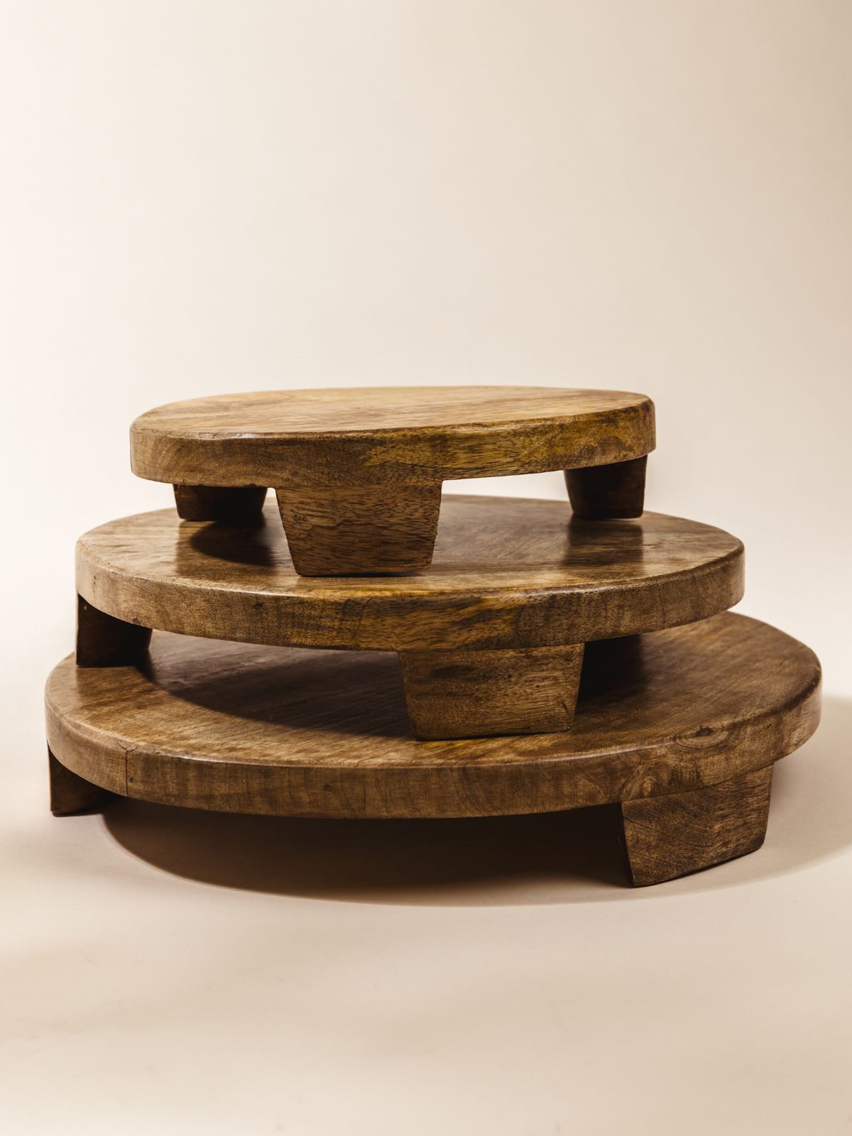 Stack of mango wood trays in small, medium, and large on cream background. 