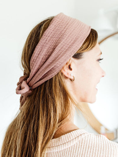 Woman wearing a blush pink fabric wrap headband tied at the back, with long hair cascading down, showcasing the headband’s comfortable and secure fit.