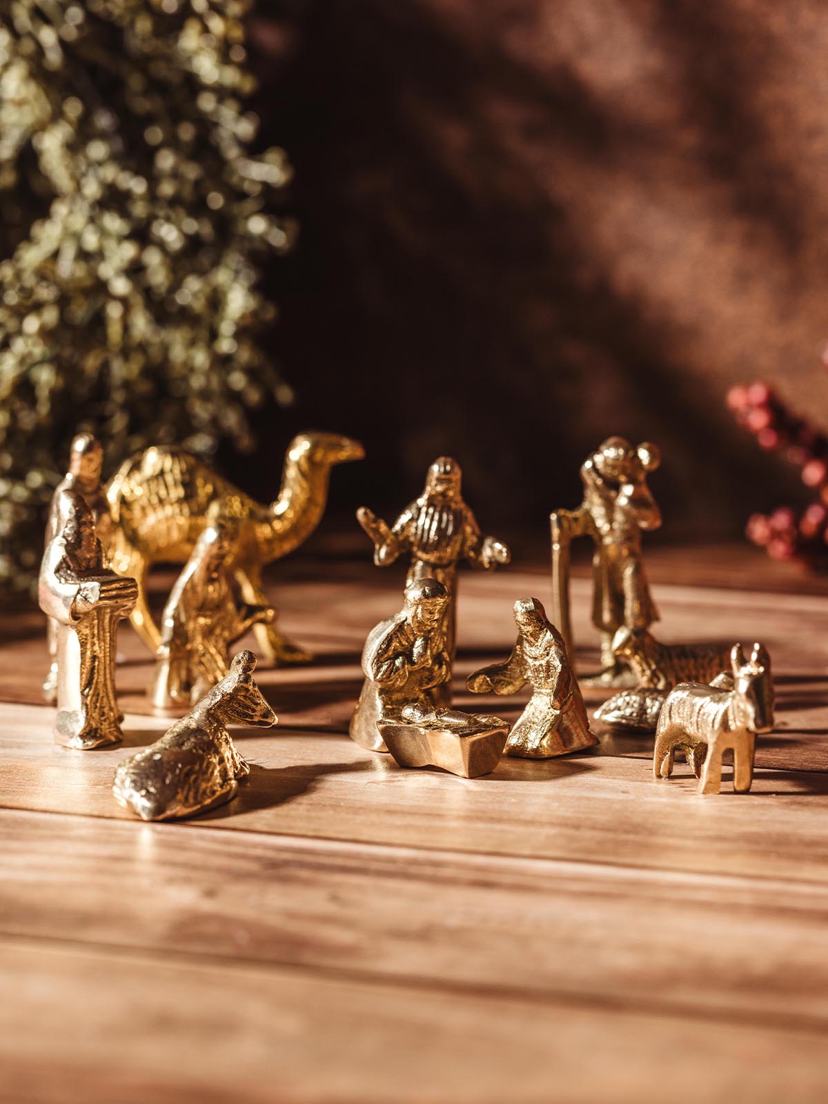 Handcrafted brass nativity scene featuring baby Jesus, Mary, Joseph, wise men, shepherds, and animals, placed on a wooden surface.