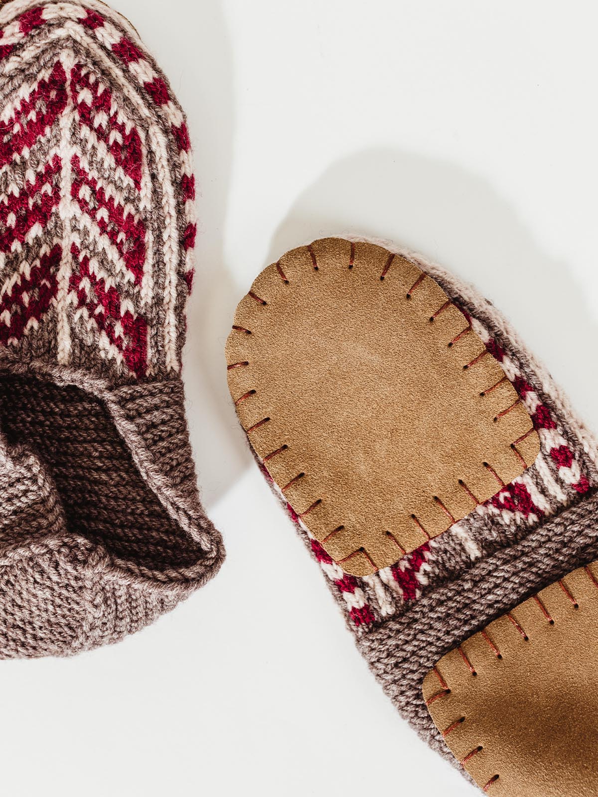 Bottom of men's tope and red slipper socks on white background.