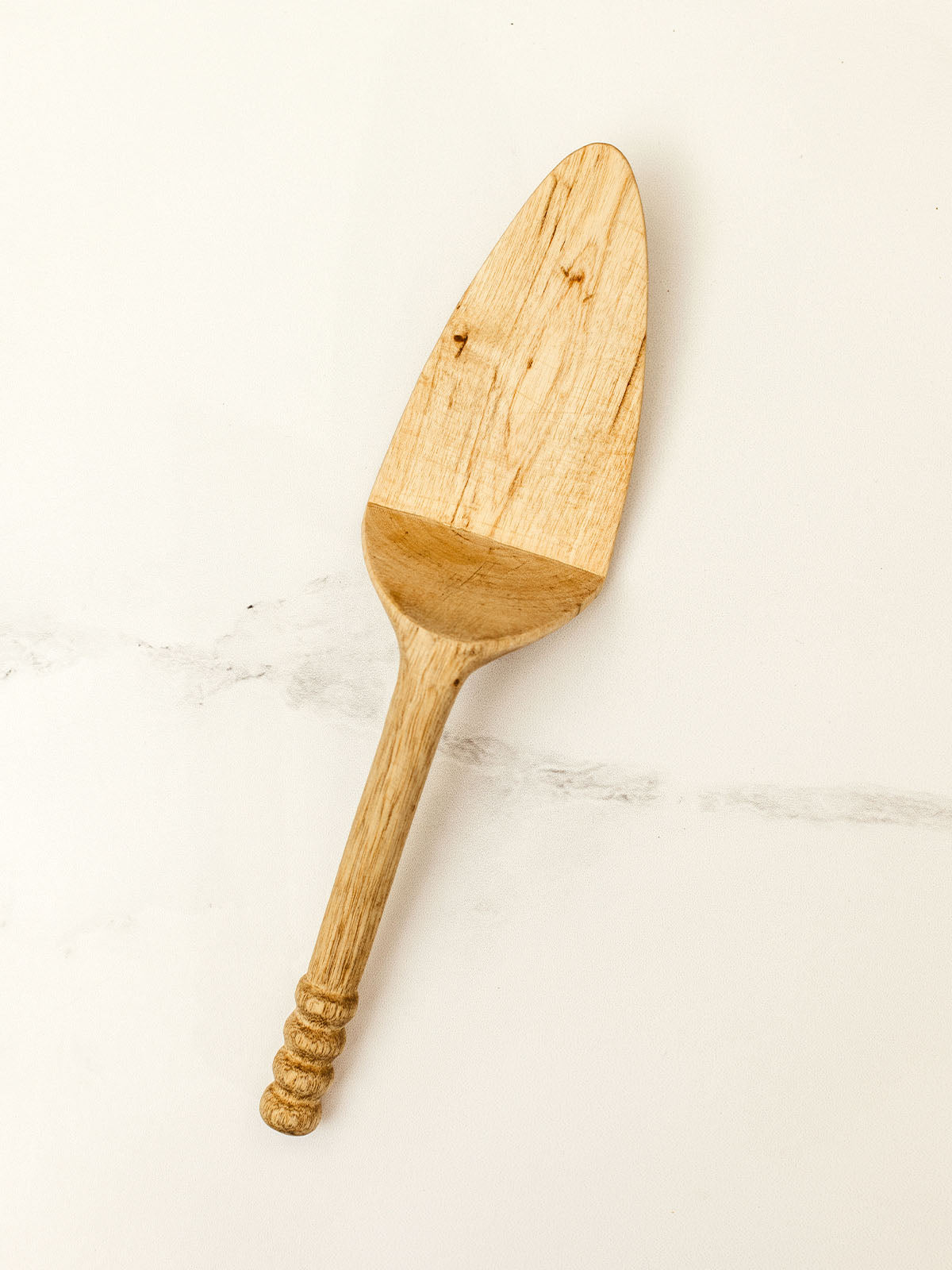 Wooden pie server on white granite counter top.