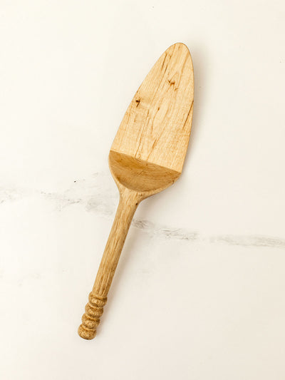 Wooden pie server on white granite counter top.