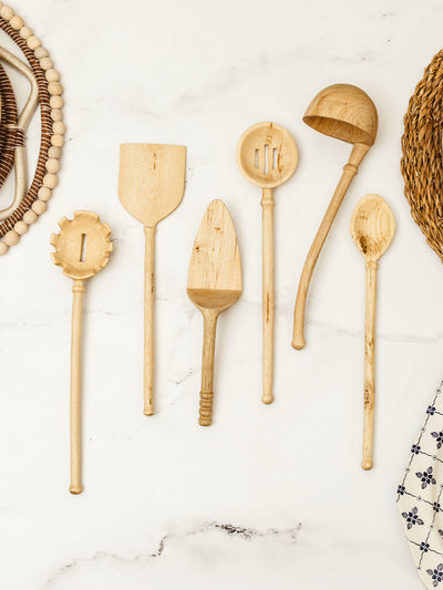 Wooden kitchen utensils on white granite counter top.