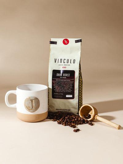 Bag of coffee and coffee scoop and mug on. a cream background.
