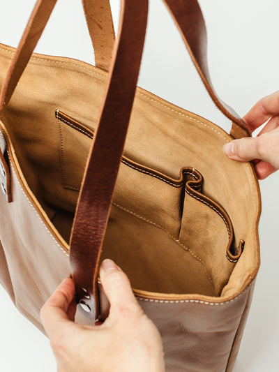 Open view of a handcrafted leather tote showing natural suede interior, slip pockets, and sturdy stitched straps. Ethically made durable leather work bag.