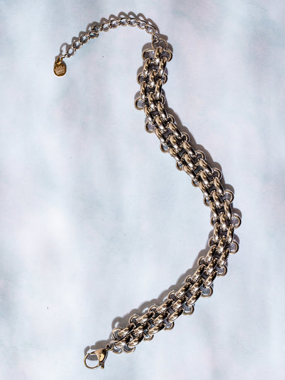 Chunky silver chain bracelet with intricate link design, displayed flat on a soft blue and white background with a lobster clasp and extender chain.