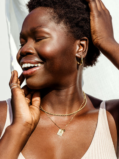 Portrait of African female model wearing hope statement gold necklace. 