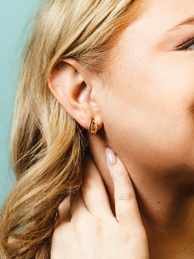 Detailed close-up of a gold beaded hoop earring on a woman’s ear. The delicate design and warm gold tone catch the light, enhancing the elegant and timeless appeal of the jewelry.