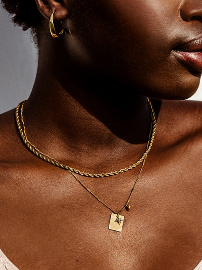 Close up of African female model wearing hope statement gold necklace. 