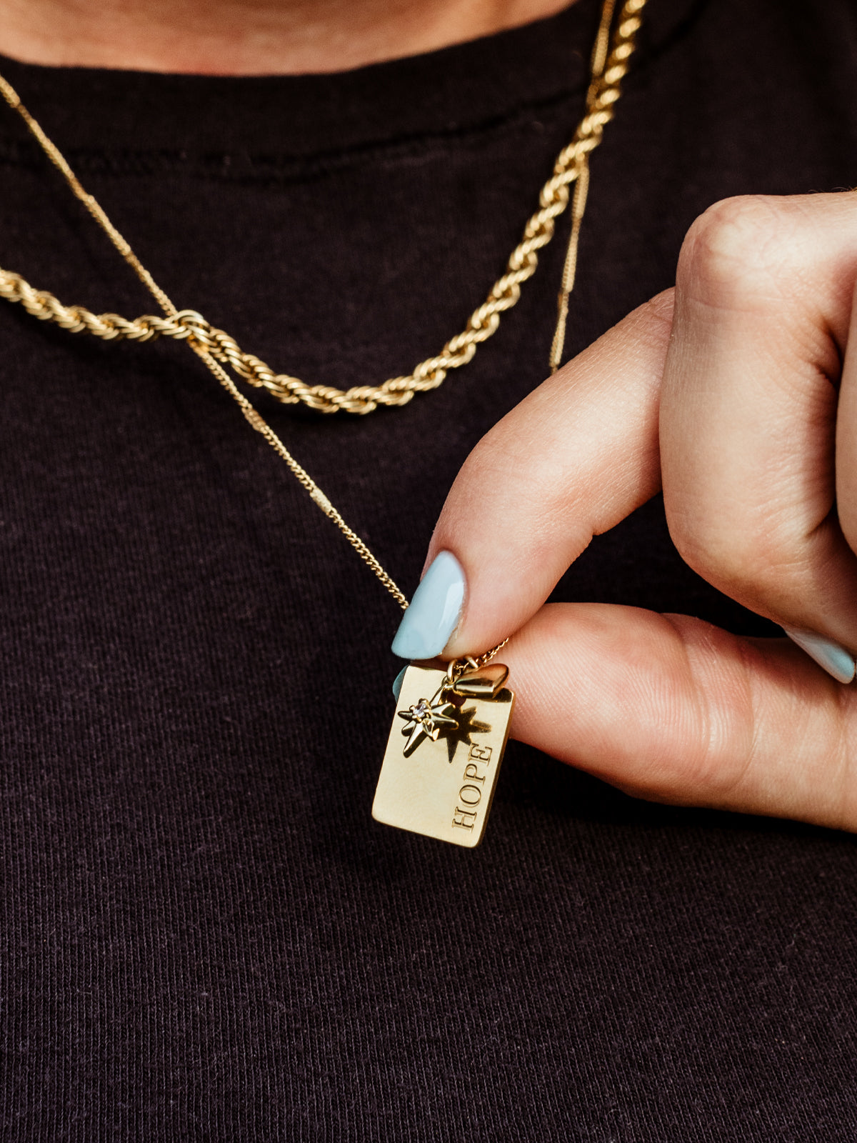 Closeup of gold hope charm on hope statement necklace. 