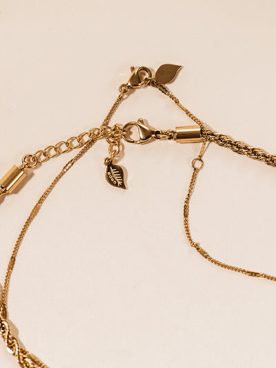 Statement gold necklace chain details and fasteners. Photographed on cream background. 