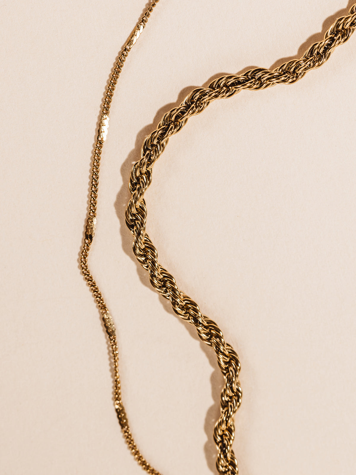 Statement gold necklace chain details. Photographed on cream background. 