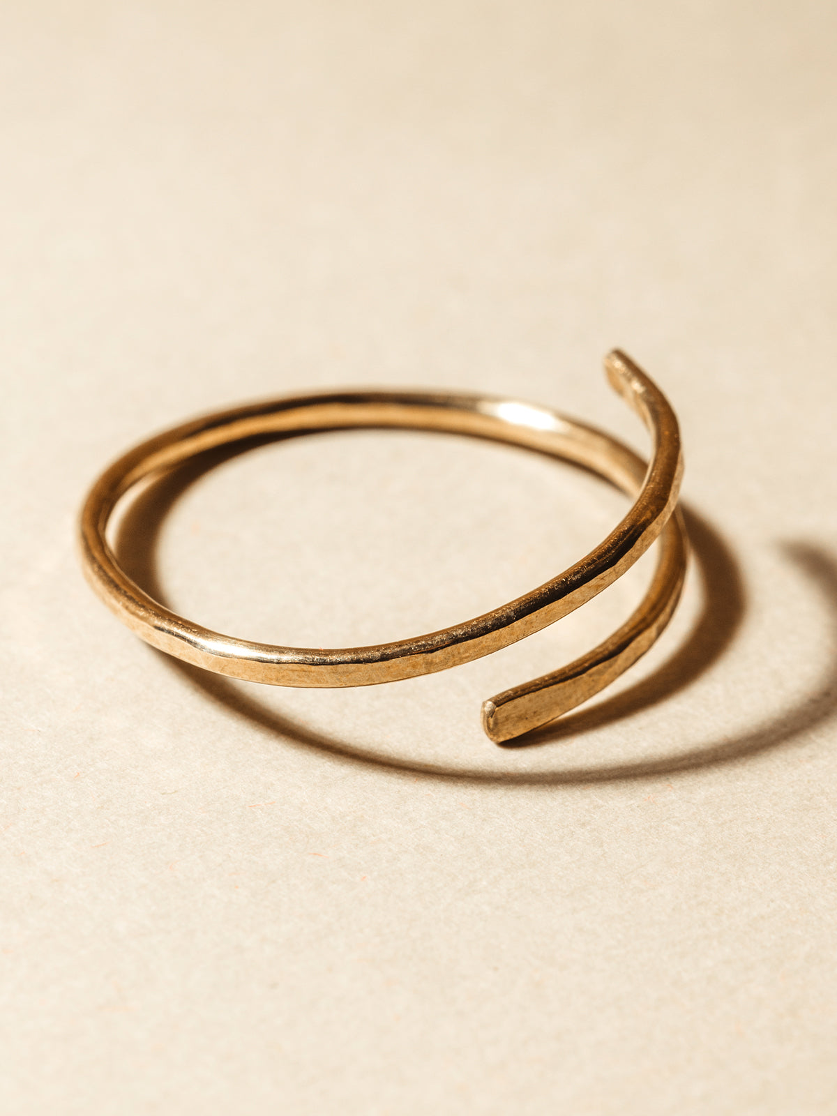 Gold hammered wrap ring on cream background.