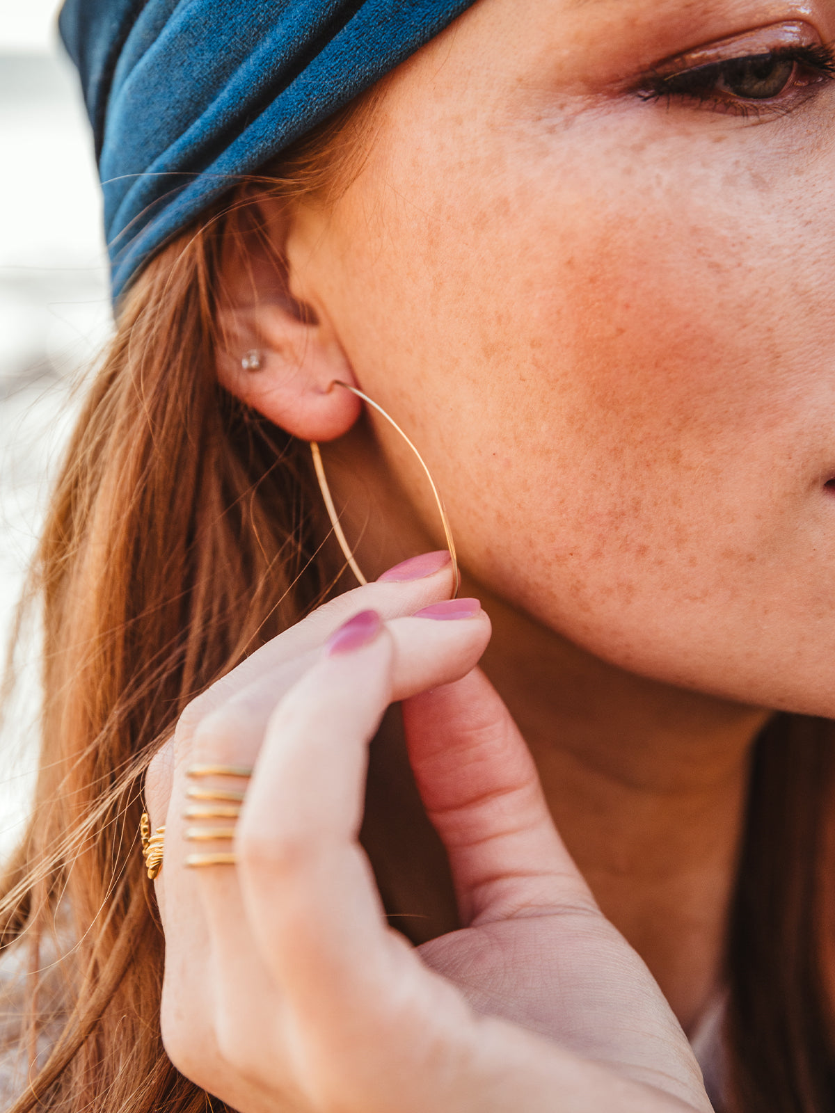 close up image of female model wearing gold hammered oval shaped earring.