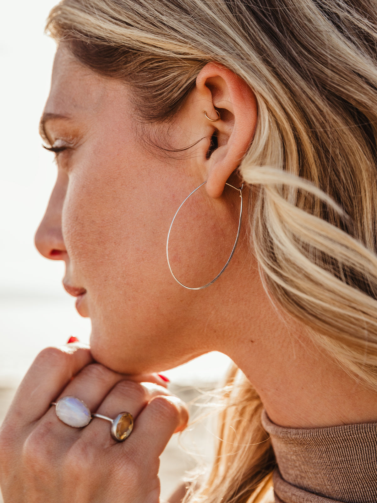 close up image of female model wearing silver hammered oval shaped earring.