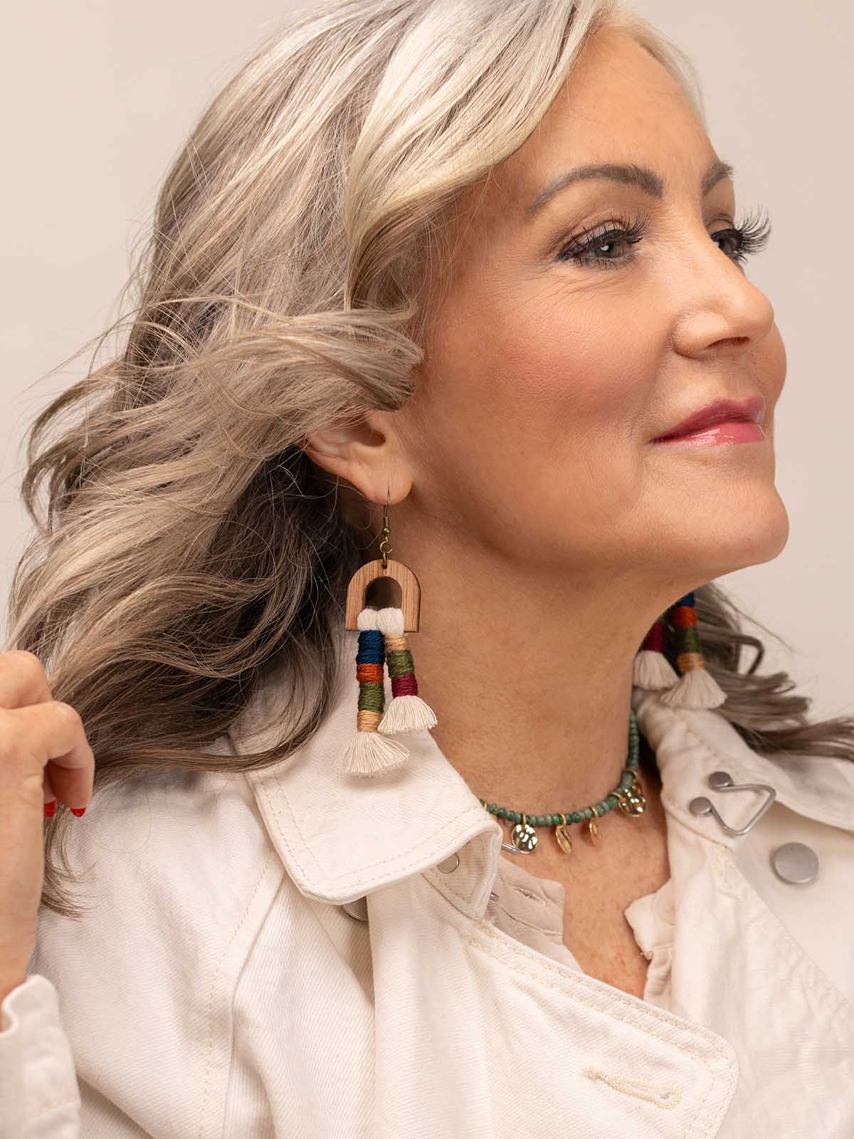 Woman wearing multicolor wood and thread tassel earrings styled for an everyday look