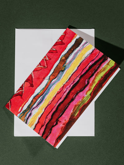 A vibrant card with layered red, pink, yellow, and green watercolor stripes, partially covering a white envelope beneath.