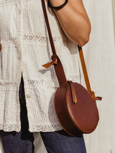 Female model with canteen purse over the shoulder In front of white fabric backdrop. 
