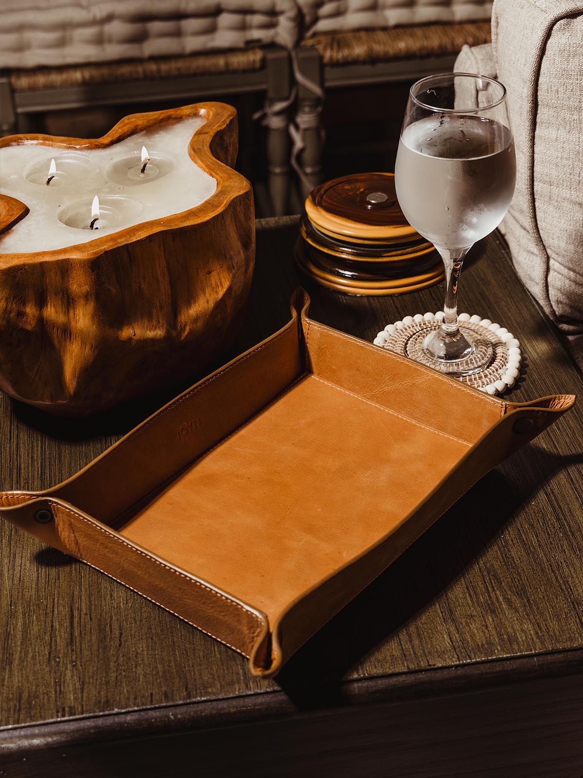Leather large valet ray on side table in living room with candle and water glass.