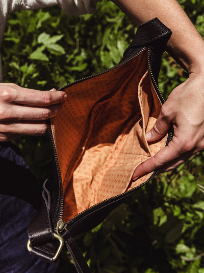 Interior view of the black leather crescent bag, showing a patterned cotton lining and interior pockets.