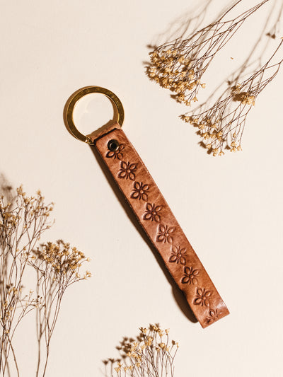 Hand Stamped Leather Keychain on cream surface with dried flowers