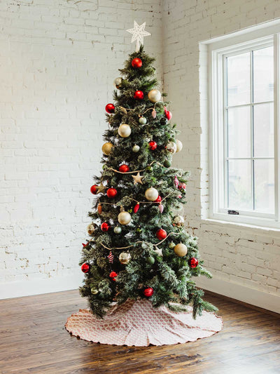 Tall decorated Christmas tree with star topper, red and gold ornaments, and a hand-block printed red and cream tree skirt — sustainable artisan-made holiday décor.