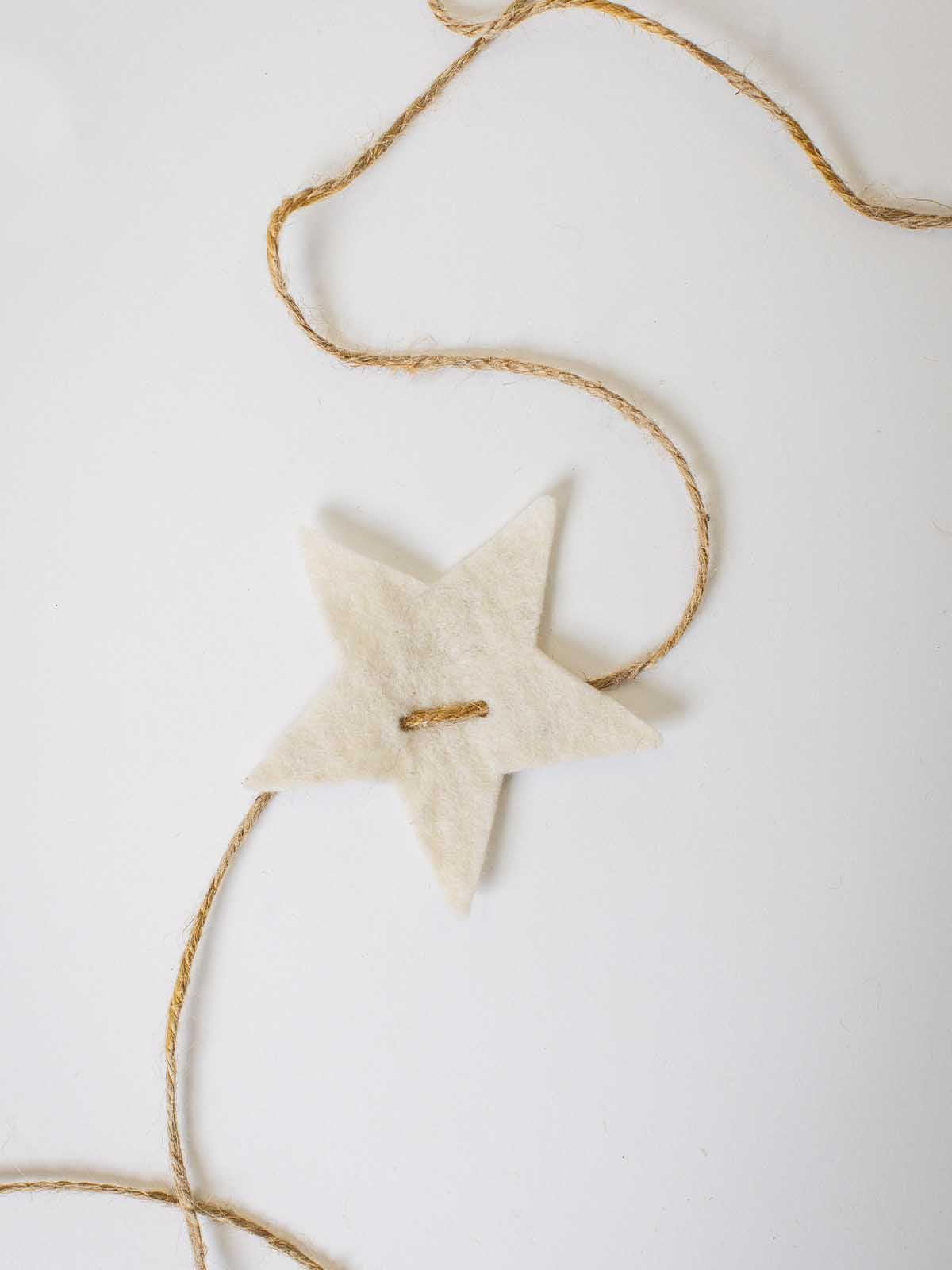 “Handcrafted felt star ornament threaded with natural jute twine — minimalist holiday decoration or gift embellishment.