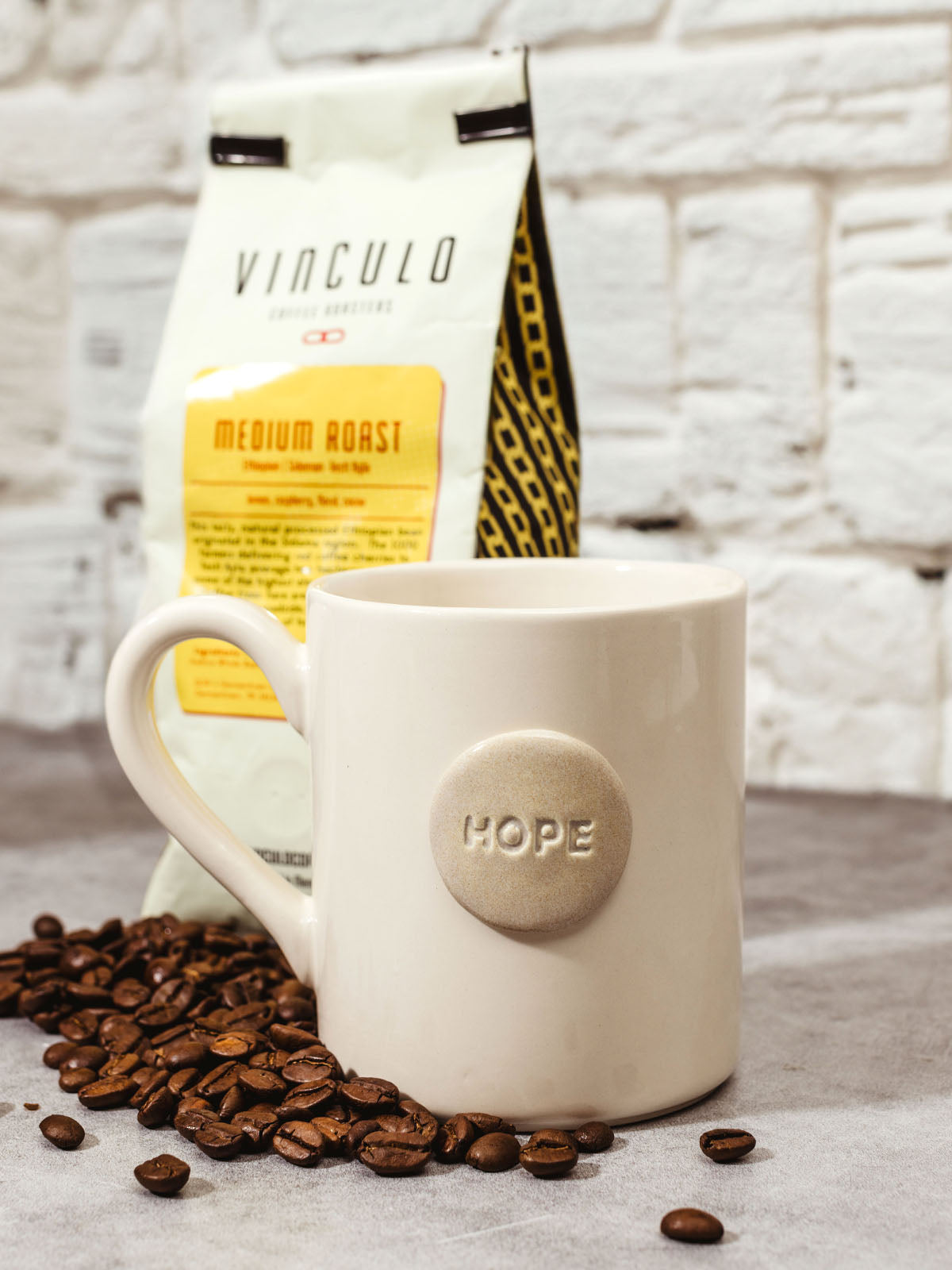 Handmade hope mug on kitchen counter with bag of coffee and spilt coffee beans.