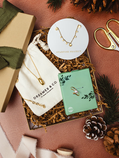 Ethical jewelry gift set with Starfish Project necklace, Dreamer & Co gold pendant, and Eden ring in holiday packaging