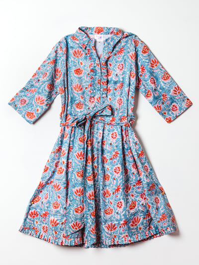 A blue floral midi dress with red and white botanical print is displayed flat on a white background. The dress includes three-quarter sleeves, a button-down front with delicate ruffle trim, and a matching fabric tie belt that cinches the waist. A pleated hem adds extra charm and femininity to the overall design.
