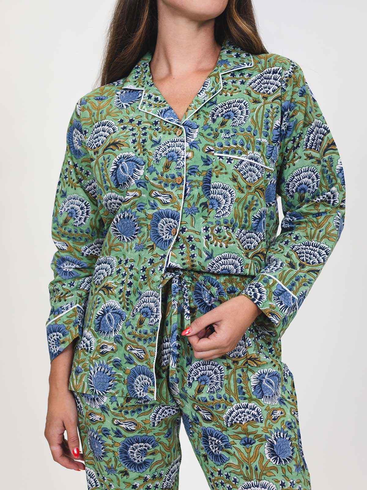 Close-up of the green and blue floral pajama set, showing button-down top, pocket with white piping, and drawstring waist pants.