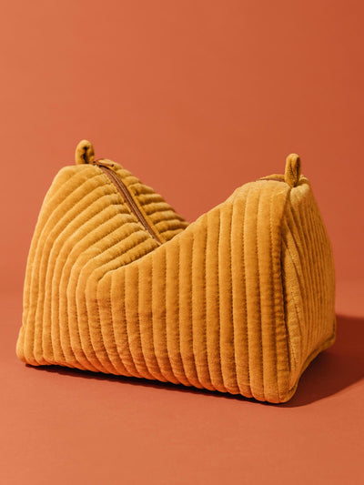 Mustard yellow velvet pouch with zipper on tuscan red background.