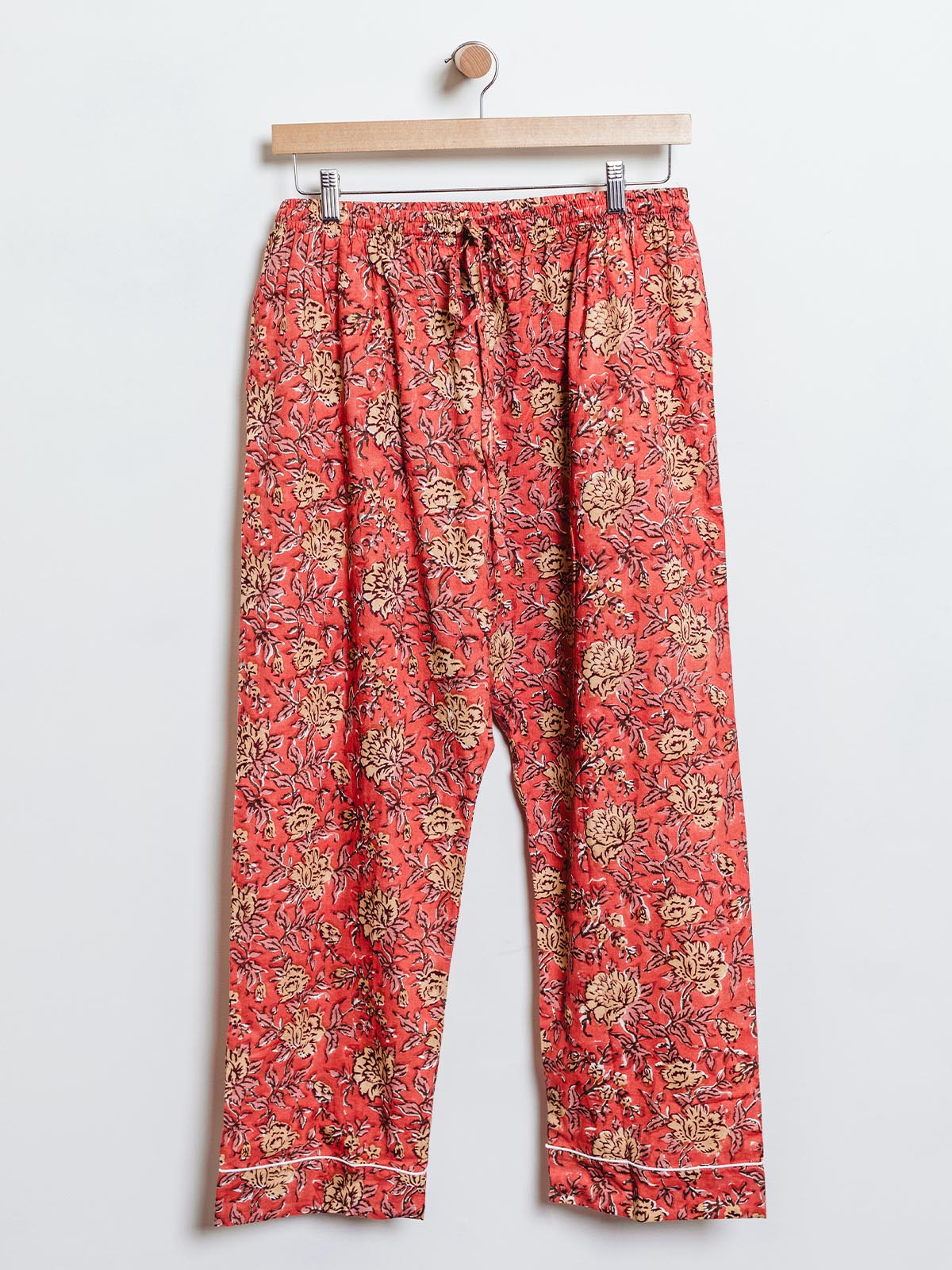 Ethically made lounge pants in vibrant red with a yellow floral pattern, designed with an elastic waistband and drawstring. These soft, handcrafted pants are perfect for casual wear or lounging, supporting sustainable fashion.