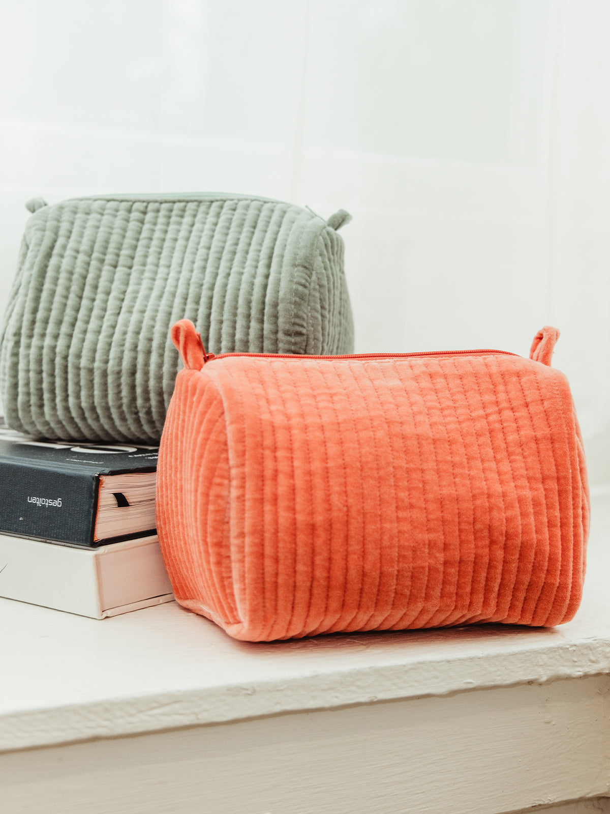 Pair of quilted velvet pouches in coral and sage green, stylish and soft storage solutions. Handcrafted by Rahab's Rope, available at Joffa.