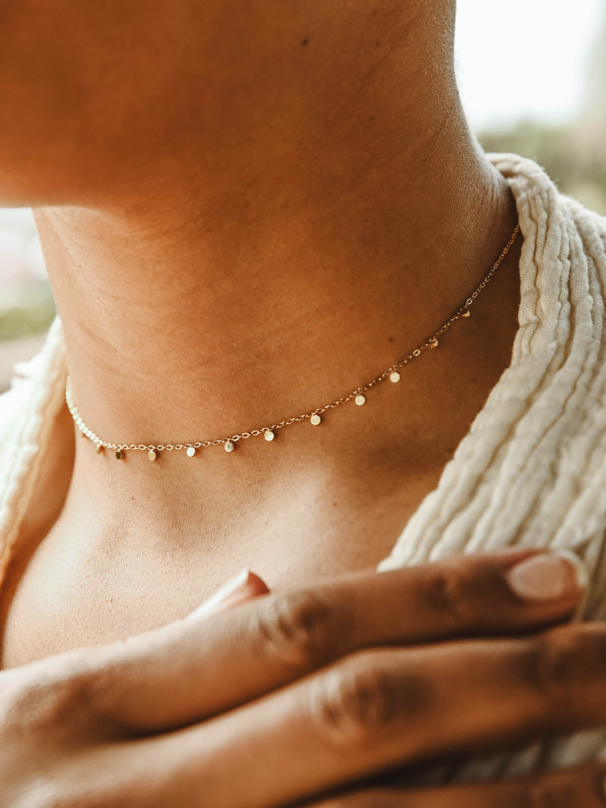 Female model wearing gold choker necklace. 