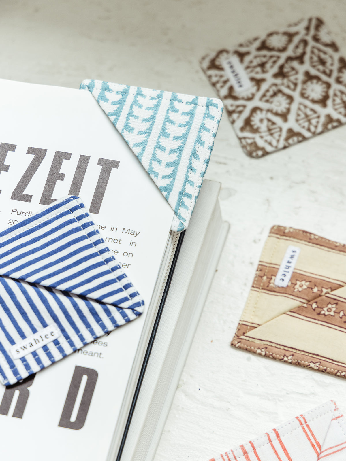 Collection of handcrafted fabric bookmarks in various colors and patterns, including blue, brown, and red. Ethical and unique reading accessories available at Joffa.com.