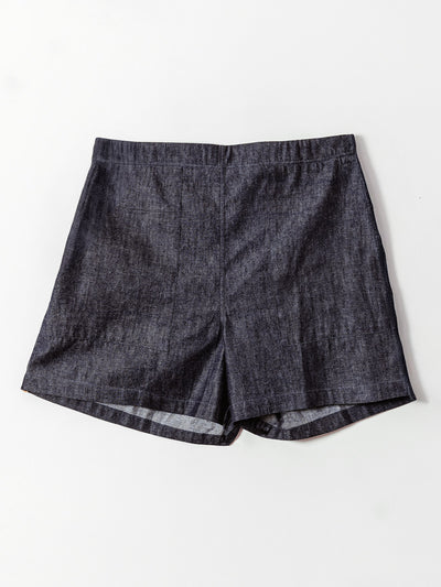 A pair of dark denim high-waisted shorts is laid flat against a light background. The shorts feature a clean, tailored front with subtle seam detailing and a slightly flared hem, offering a structured yet casual look.