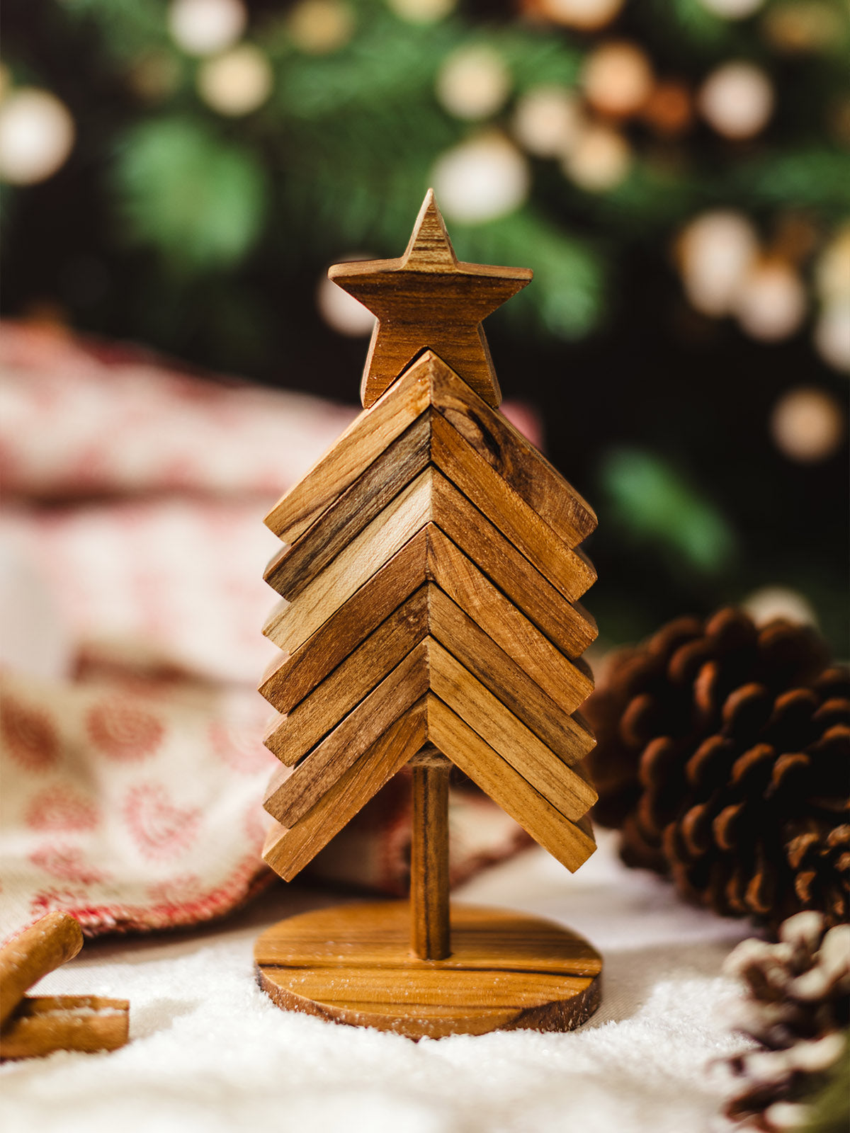 Handcrafted wooden Christmas tree with star topper, rustic holiday décor styled with pinecones, cinnamon sticks, and cozy festive background.