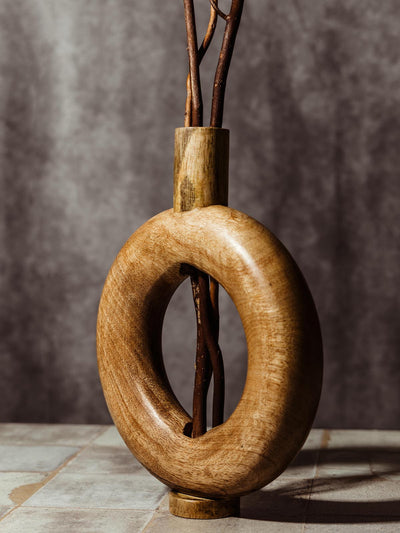 Handcrafted wooden vase with a modern circular design, featuring natural wood grain and branches arranged through the center. This ethically made home decor piece adds a rustic and elegant touch to any space, highlighting sustainable craftsmanship.