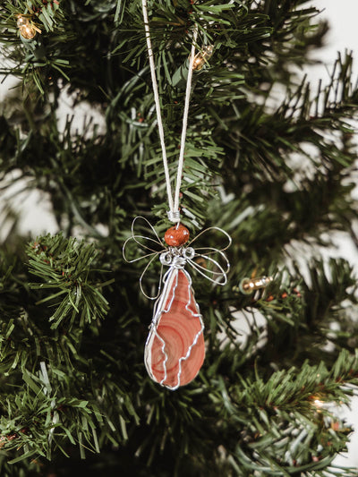 Handmade stone and wire angel shaped holiday ornament  hangin on a holiday tree.