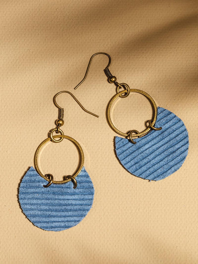 Golden hoop wont texture blue paper accent laying on a tan surface.