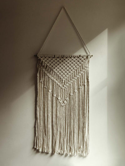 White Macrame wall hanging on white wall.