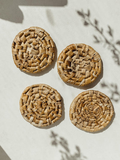 Four banana leaf coasters on a white surface.