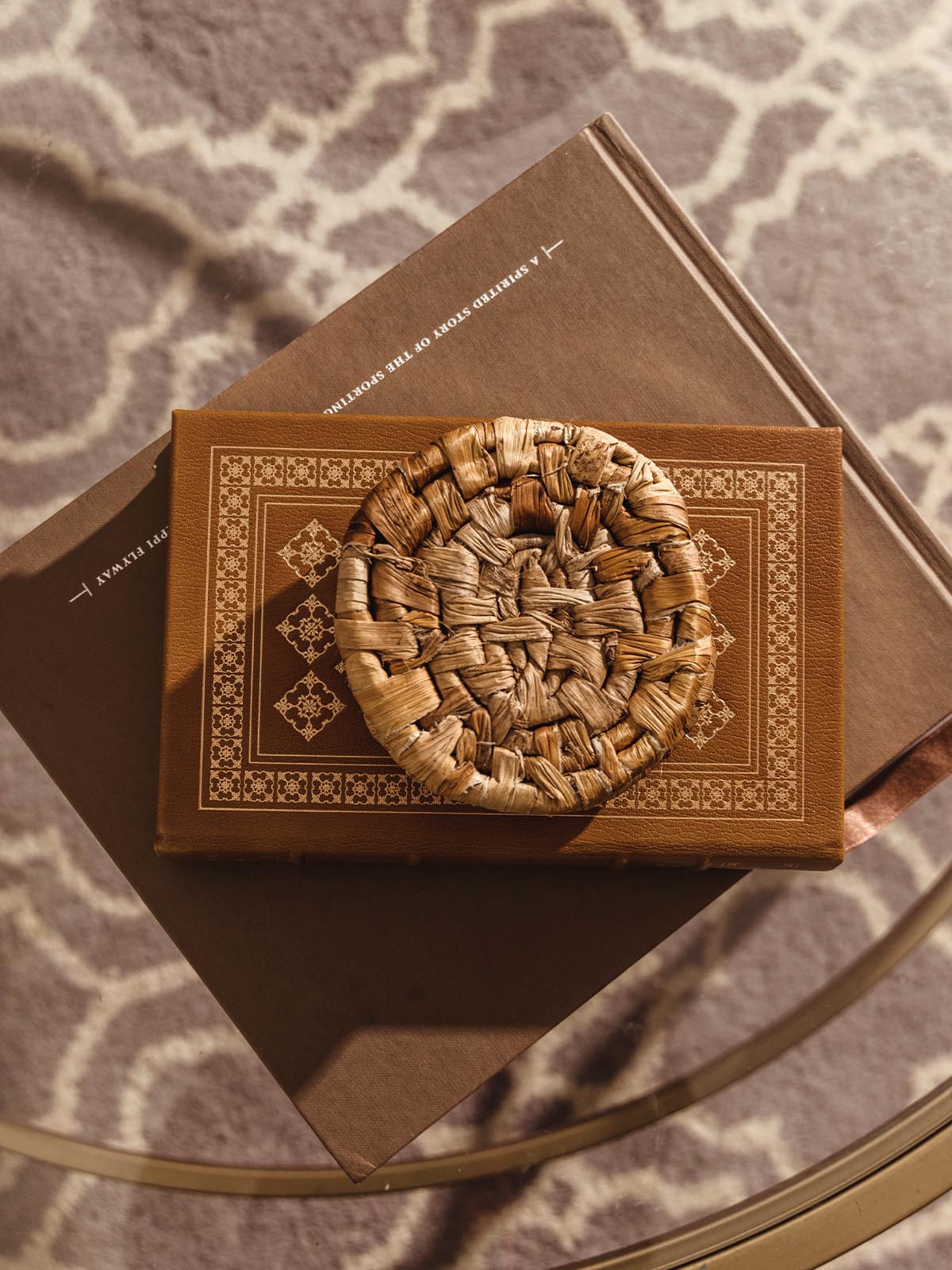 One banana leaf coaster onto of books on a glass table