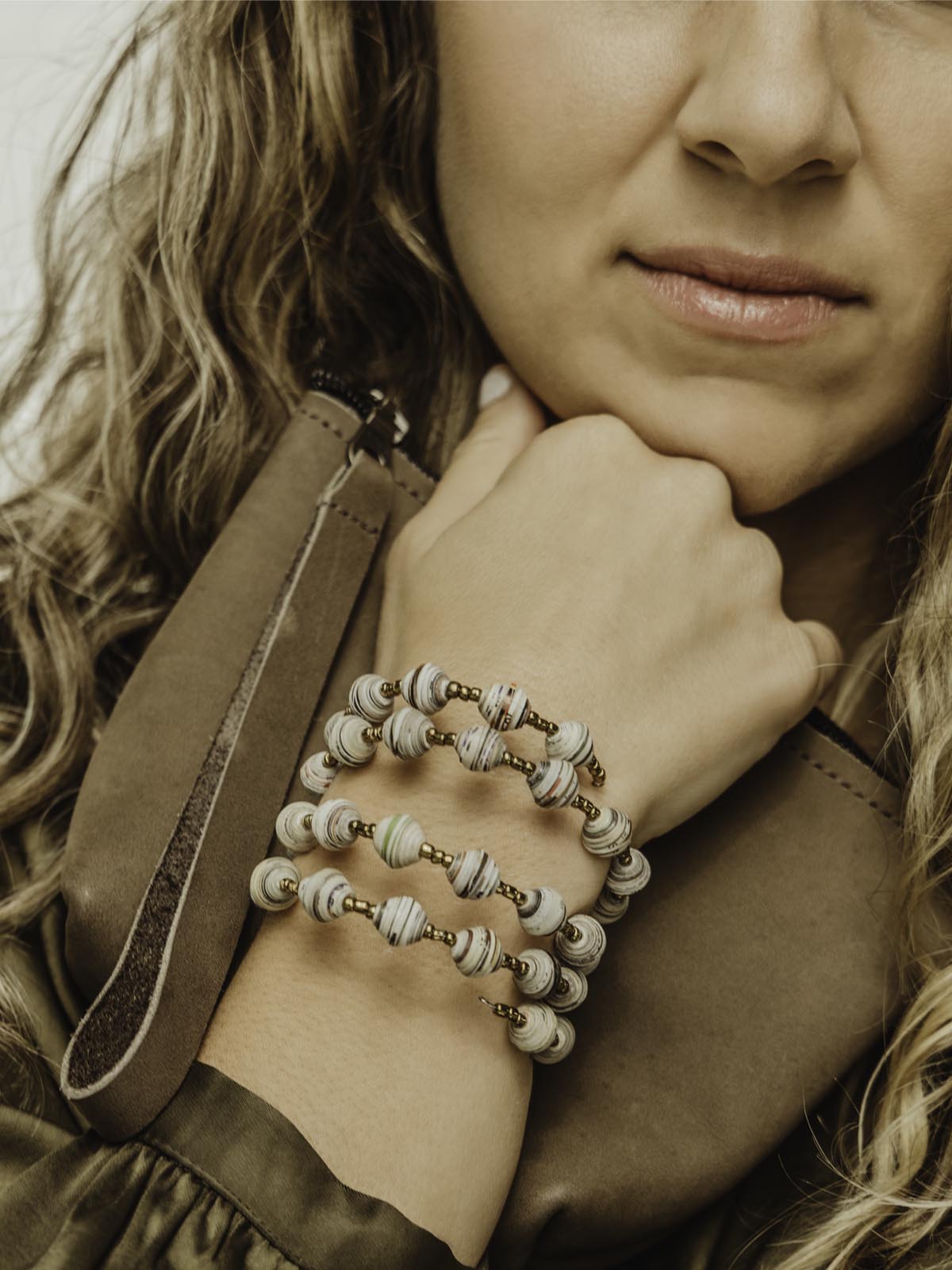 Wrap bracelet with golden and white beading on a female model holding a wristlet purse.